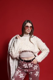 Photo of Fashionable portrait of beautiful woman in stylish outfit on red background