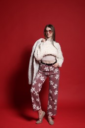 Photo of Fashionable full-length portrait of beautiful woman in stylish outfit on red background
