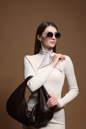 Photo of Fashionable portrait of beautiful woman in stylish outfit on brown background