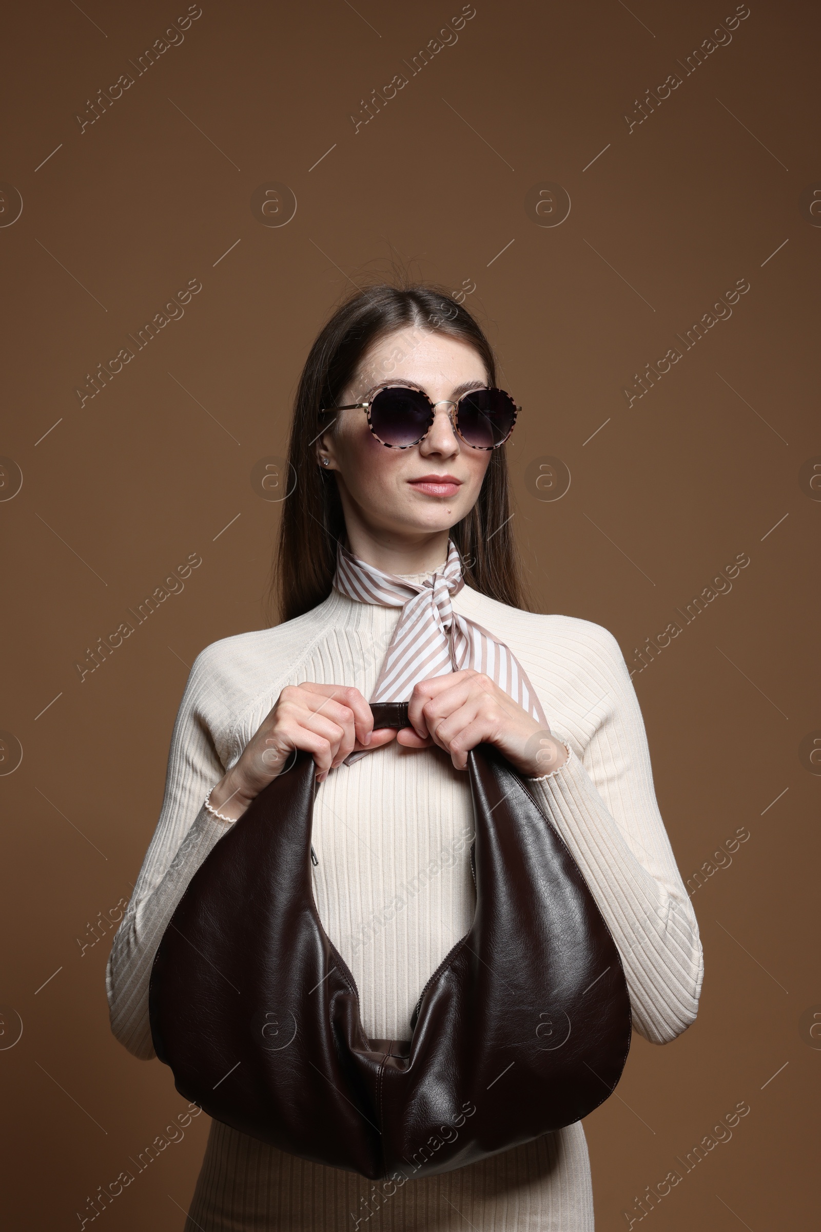 Fashionable portrait of beautiful woman in stylish outfit on brown background Photo of Fashionable portrait of beautiful woman in stylish outfit on brown background