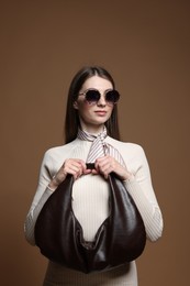 Photo of Fashionable portrait of beautiful woman in stylish outfit on brown background