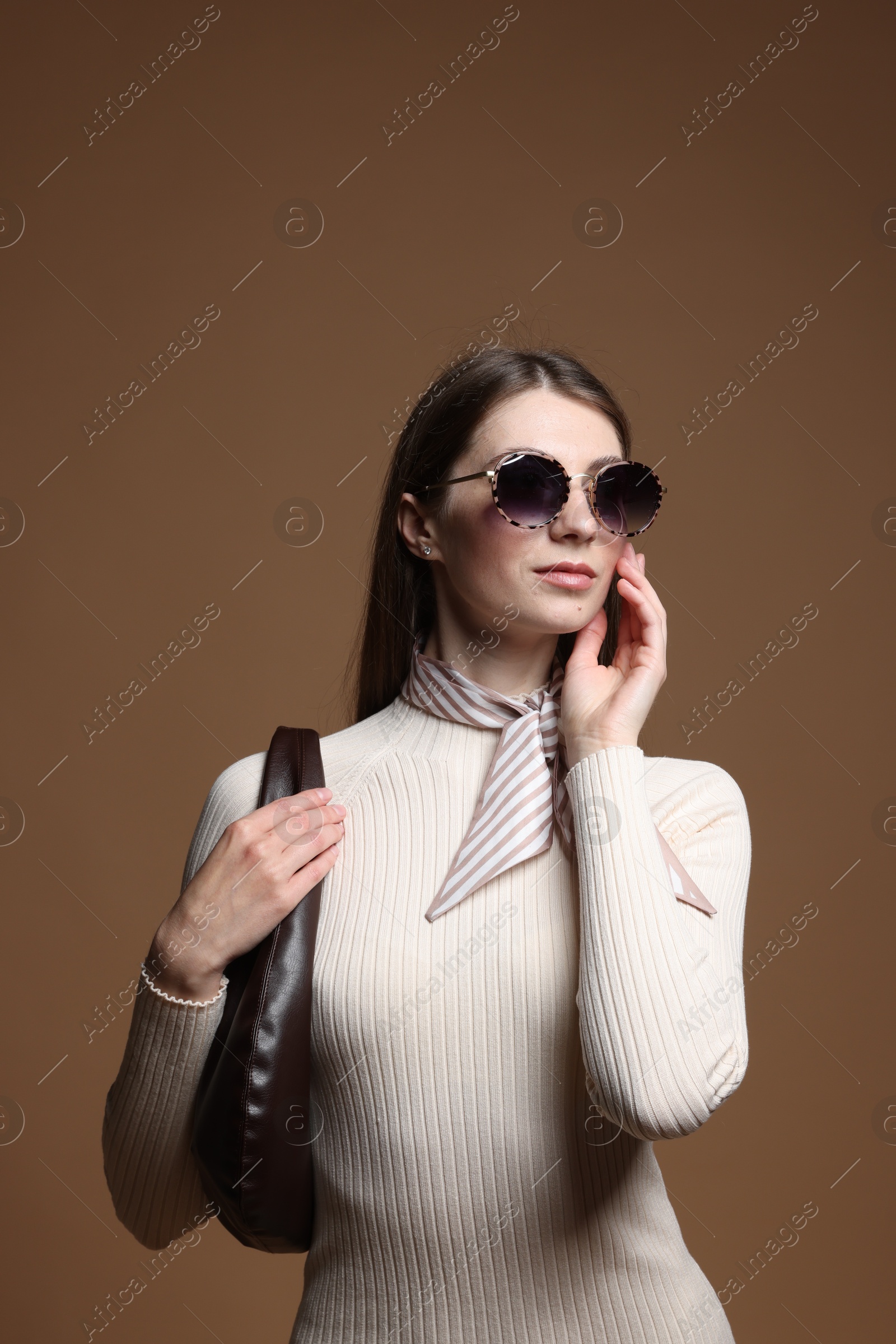 Fashionable portrait of beautiful woman in stylish outfit on brown background Photo of Fashionable portrait of beautiful woman in stylish outfit on brown background