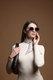 Photo of Fashionable portrait of beautiful woman in stylish outfit on brown background