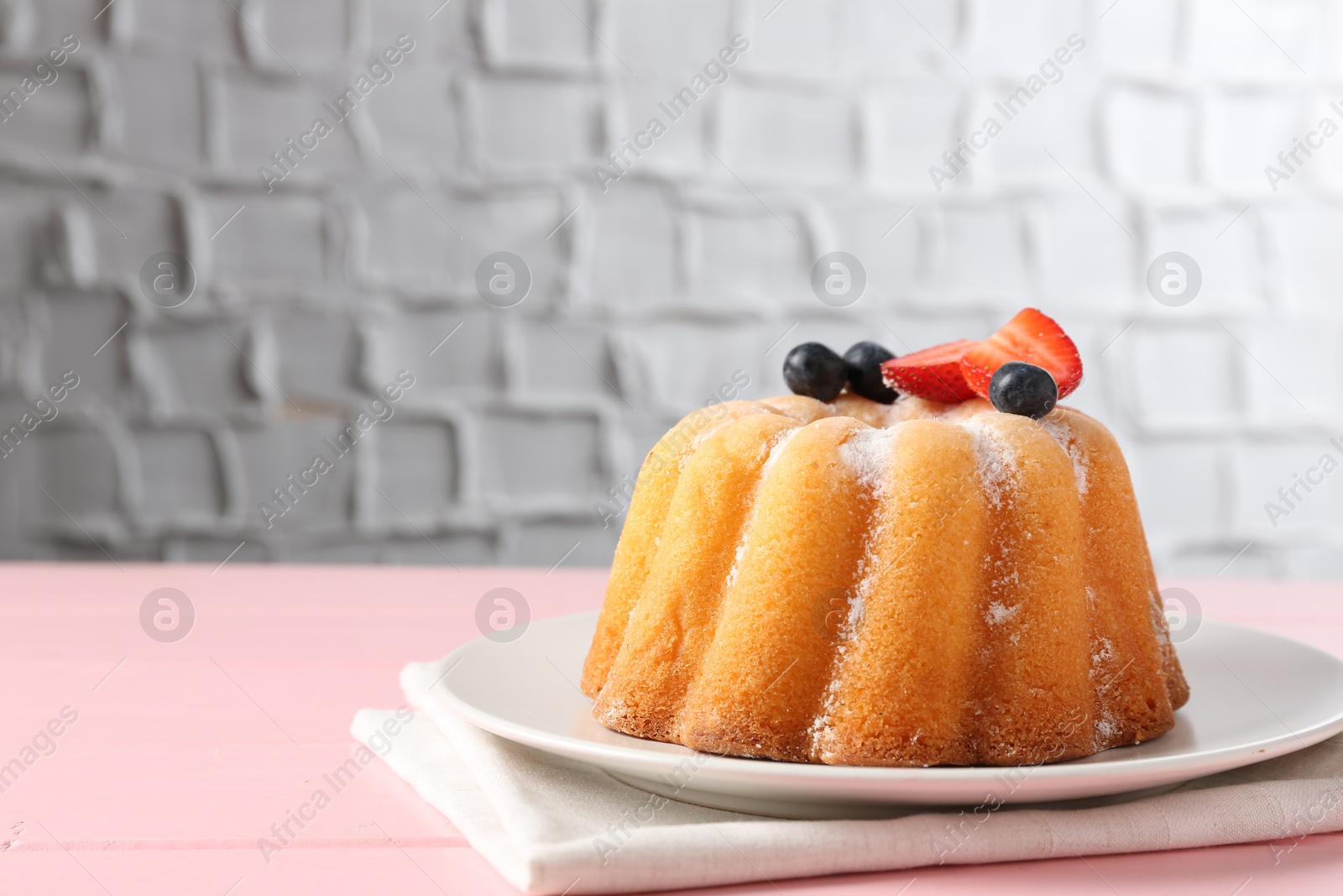 Tasty Bundt cake with powdered sugar and berries on pink wooden table, closeup. Space for text Photo of Tasty Bundt cake with powdered sugar and berries on pink wooden table, closeup. Space for text