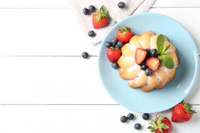 Photo of Tasty Bundt cake with powdered sugar and berries on white wooden table, flat lay. Space for text