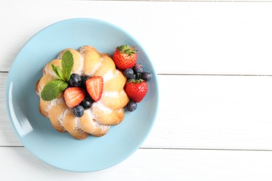 Photo of Tasty Bundt cake with powdered sugar and berries on white wooden table, top view. Space for text