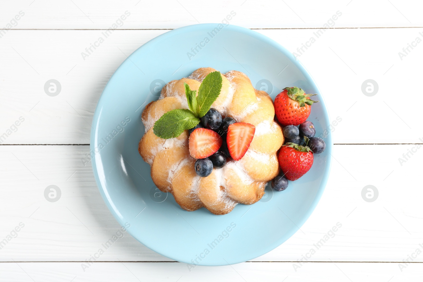 Tasty Bundt cake with powdered sugar and berries on white wooden table, top view Photo of Tasty Bundt cake with powdered sugar and berries on white wooden table, top view