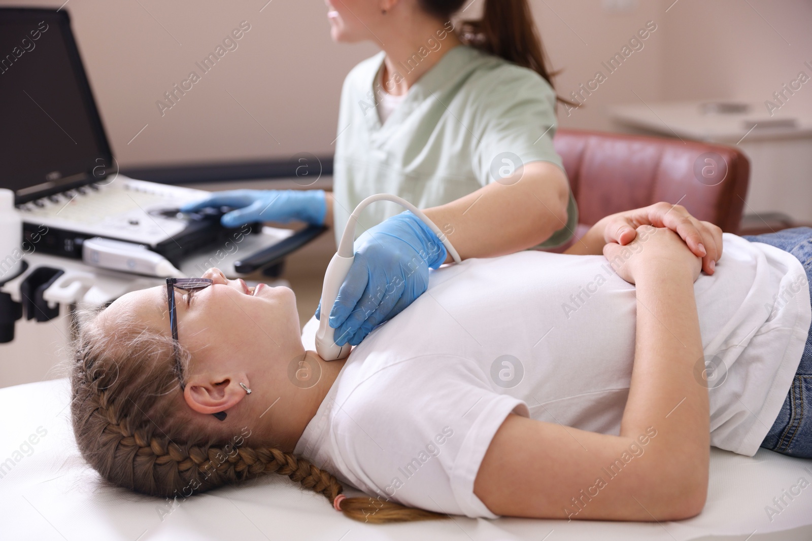 Sonographer conducting girl's thyroid gland ultrasound examination in clinic, closeup Photo of Sonographer conducting girl's thyroid gland ultrasound examination in clinic, closeup