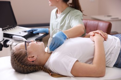 Photo of Sonographer conducting girl's thyroid gland ultrasound examination in clinic, closeup