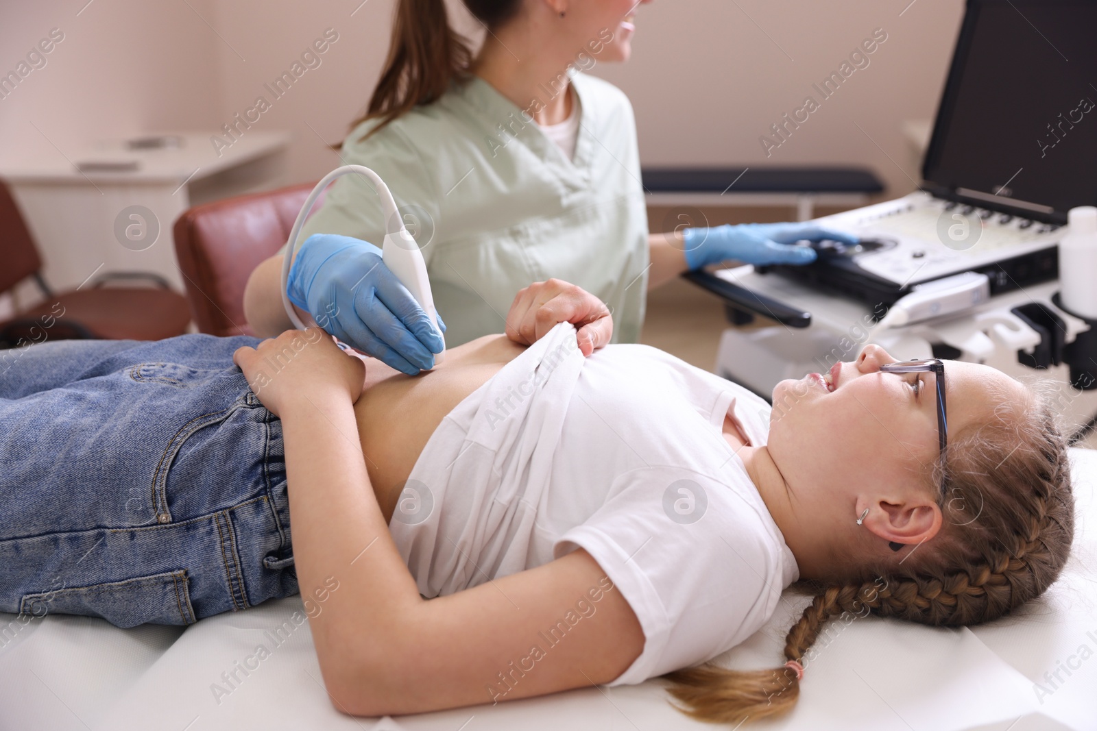 Sonographer conducting girl's abdominal ultrasound examination in clinic, closeup Photo of Sonographer conducting girl's abdominal ultrasound examination in clinic, closeup