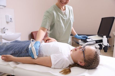 Photo of Sonographer conducting ultrasound examination of girl's arm in clinic, closeup