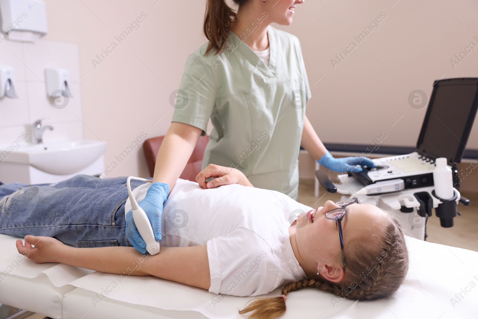 Sonographer conducting ultrasound examination of girl's arm in clinic, closeup Photo of Sonographer conducting ultrasound examination of girl's arm in clinic, closeup