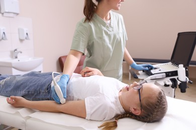 Photo of Sonographer conducting ultrasound examination of girl's arm in clinic, closeup