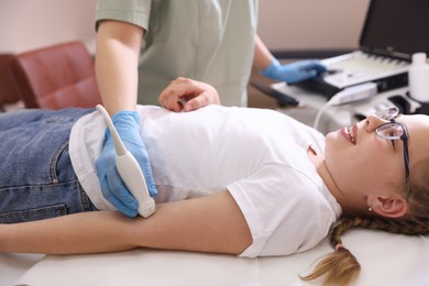 Photo of Sonographer conducting ultrasound examination of girl's arm in clinic, closeup