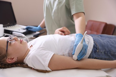 Photo of Sonographer conducting ultrasound examination of girl's arm in clinic, closeup