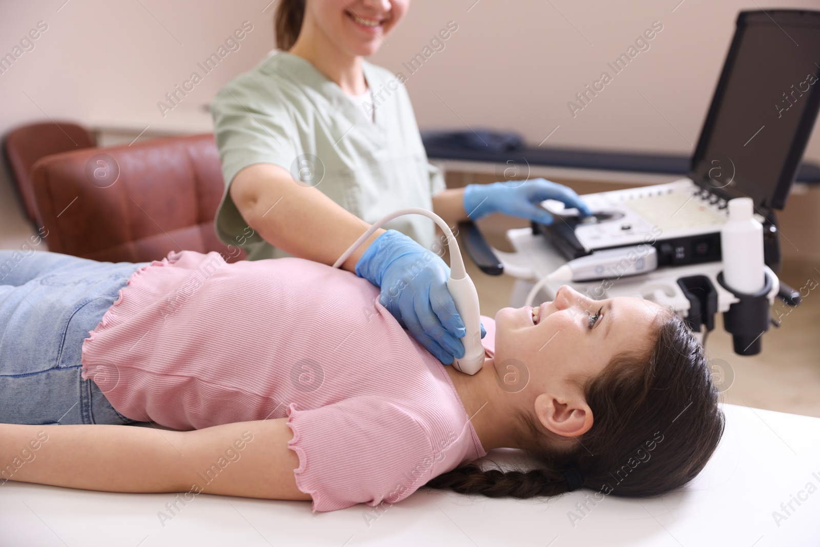 Sonographer conducting girl's thyroid gland ultrasound examination in clinic, closeup Photo of Sonographer conducting girl's thyroid gland ultrasound examination in clinic, closeup