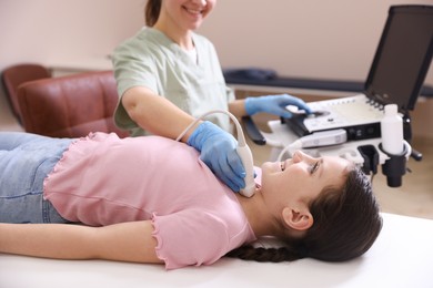 Photo of Sonographer conducting girl's thyroid gland ultrasound examination in clinic, closeup