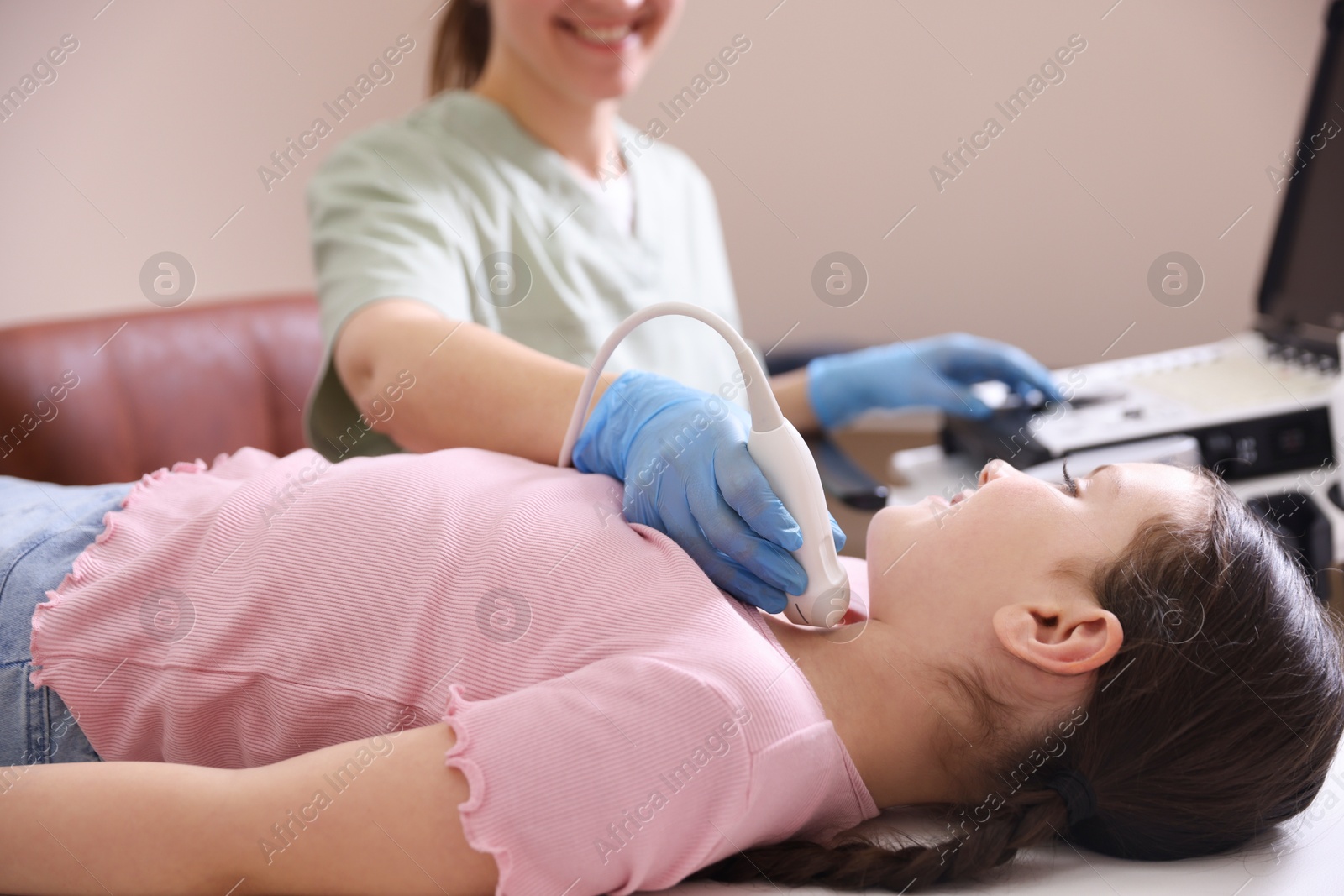 Sonographer conducting girl's thyroid gland ultrasound examination in clinic, closeup Photo of Sonographer conducting girl's thyroid gland ultrasound examination in clinic, closeup