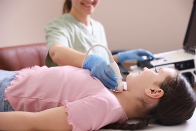 Photo of Sonographer conducting girl's thyroid gland ultrasound examination in clinic, closeup