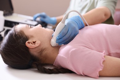 Photo of Sonographer conducting girl's thyroid gland ultrasound examination in clinic, closeup