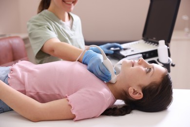 Photo of Sonographer conducting girl's thyroid gland ultrasound examination in clinic, closeup