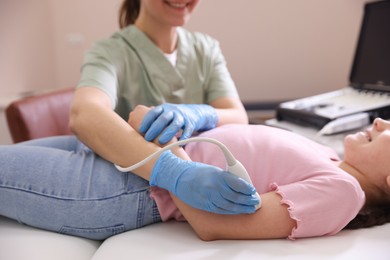 Photo of Sonographer conducting ultrasound examination of girl's arm in clinic, closeup