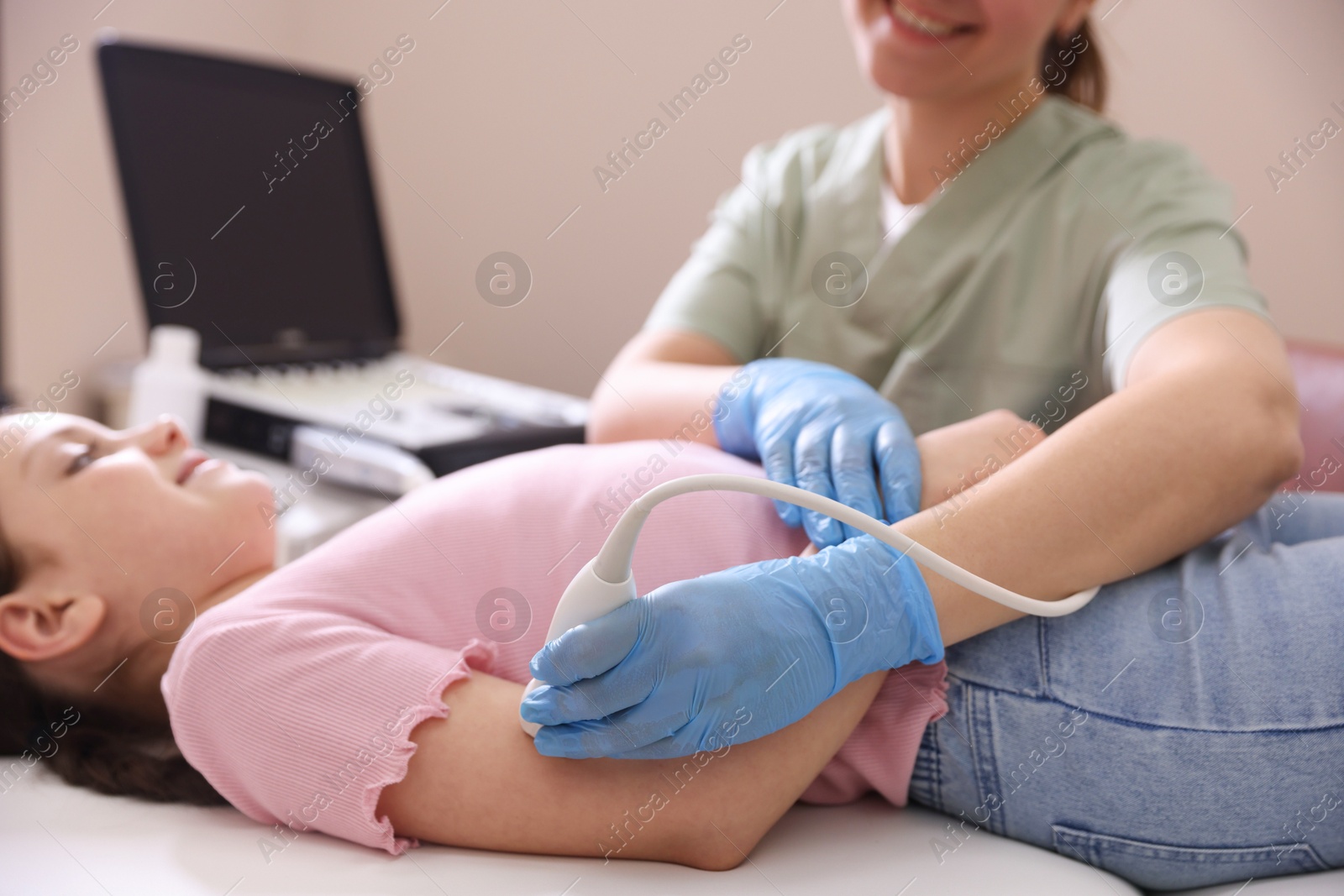 Sonographer conducting ultrasound examination of girl's arm in clinic, closeup Photo of Sonographer conducting ultrasound examination of girl's arm in clinic, closeup