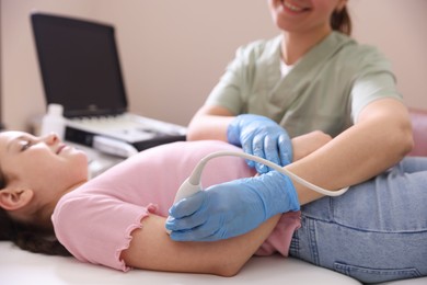 Photo of Sonographer conducting ultrasound examination of girl's arm in clinic, closeup