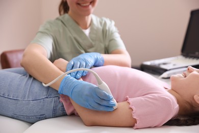 Photo of Sonographer conducting ultrasound examination of girl's arm in clinic, closeup