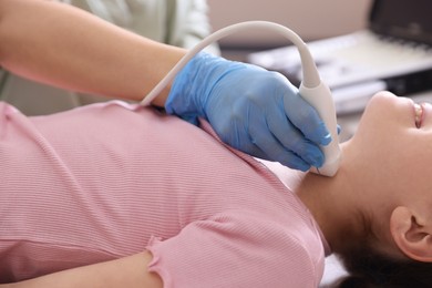 Photo of Sonographer conducting girl's thyroid gland ultrasound examination in clinic, closeup