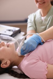 Photo of Sonographer conducting girl's thyroid gland ultrasound examination in clinic, closeup