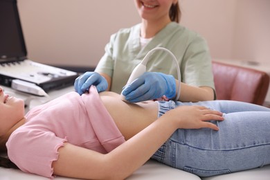 Photo of Sonographer conducting girl's abdominal ultrasound examination in clinic, closeup