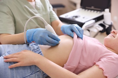 Photo of Sonographer conducting girl's abdominal ultrasound examination in clinic, closeup