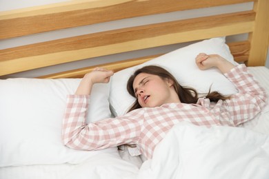 Photo of Young woman stretching on bed at home
