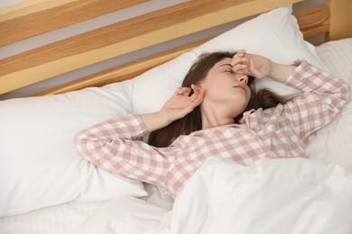 Photo of Young woman stretching on bed at home