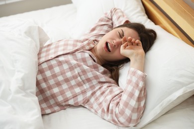Photo of Young woman stretching on bed at home
