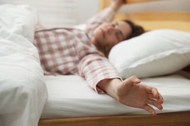 Photo of Young woman stretching on bed at home, selective focus