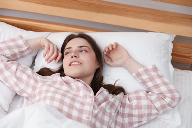 Photo of Young woman stretching on bed at home