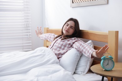 Photo of Young woman stretching on bed at home