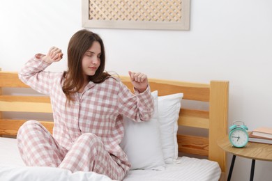 Photo of Young woman stretching on bed at home