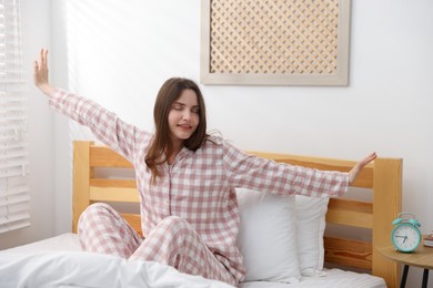 Photo of Young woman stretching on bed at home