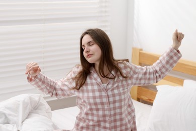 Photo of Young woman stretching on bed at home