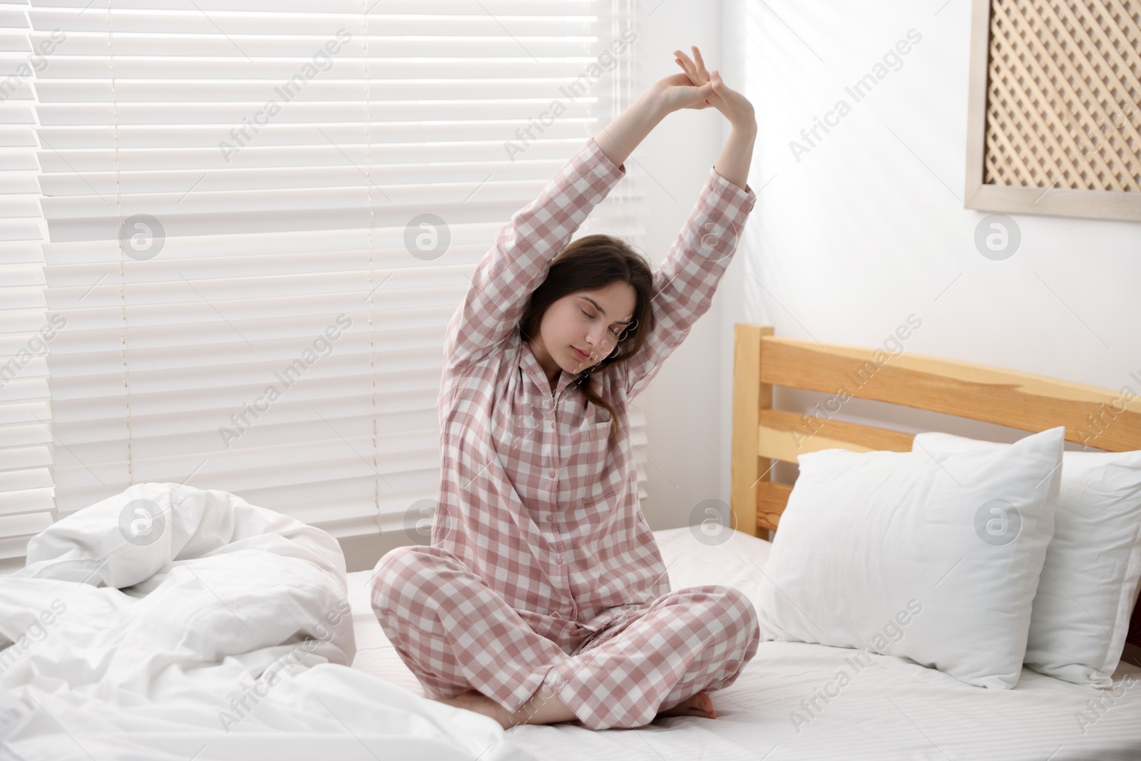 Young woman stretching on bed at home Photo of Young woman stretching on bed at home