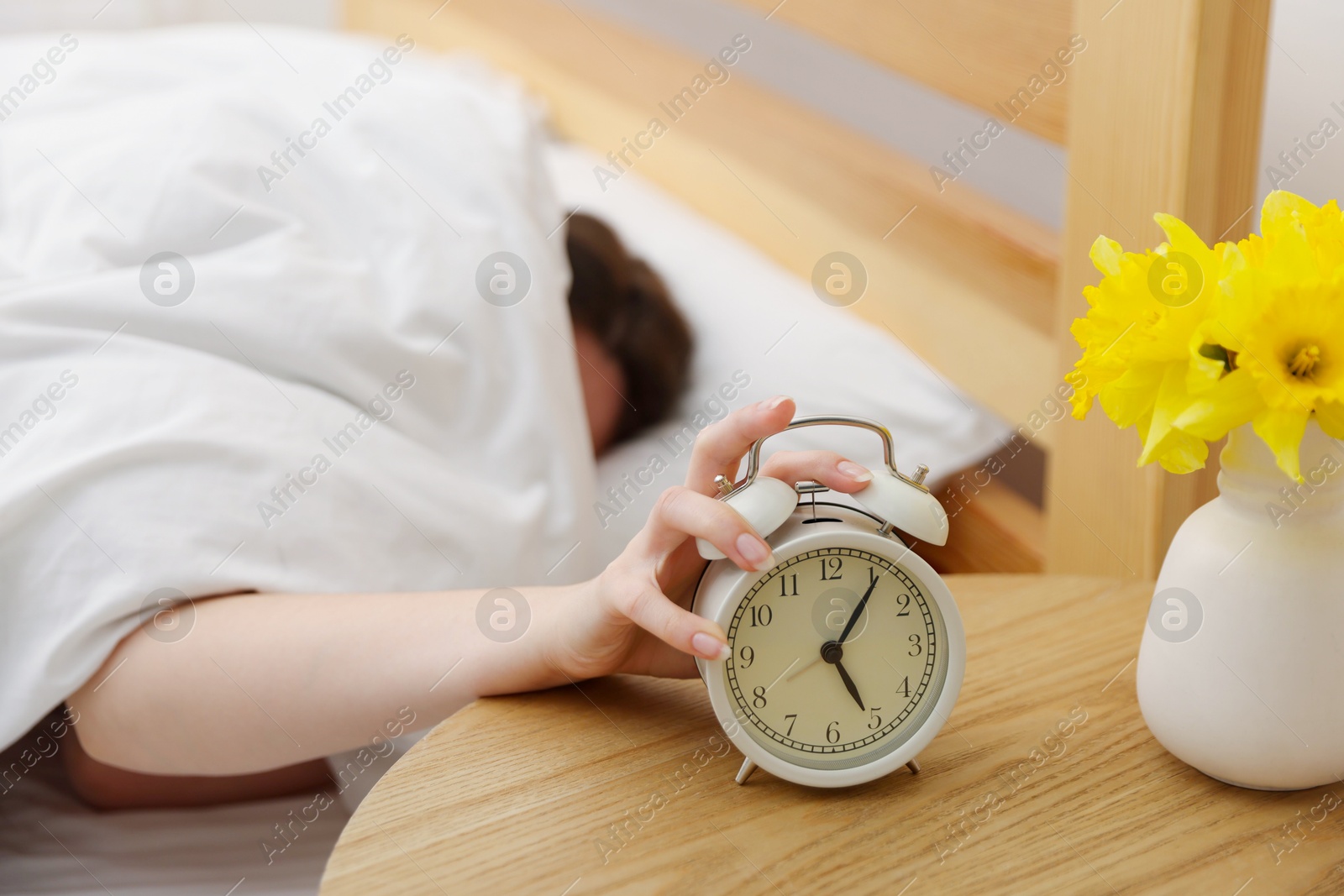Woman turning off alarm clock on bed at home, selective focus Photo of Woman turning off alarm clock on bed at home, selective focus