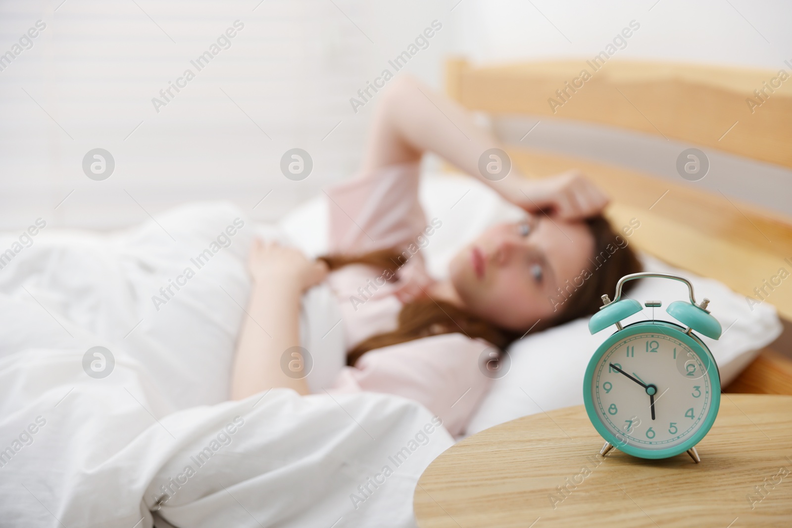 Frustrated young woman on bed at home, focus on alarm clock Photo of Frustrated young woman on bed at home, focus on alarm clock