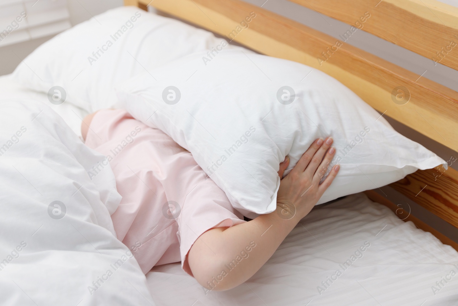 Woman covering herself with pillow on bed at home. Insomnia problem Photo of Woman covering herself with pillow on bed at home. Insomnia problem