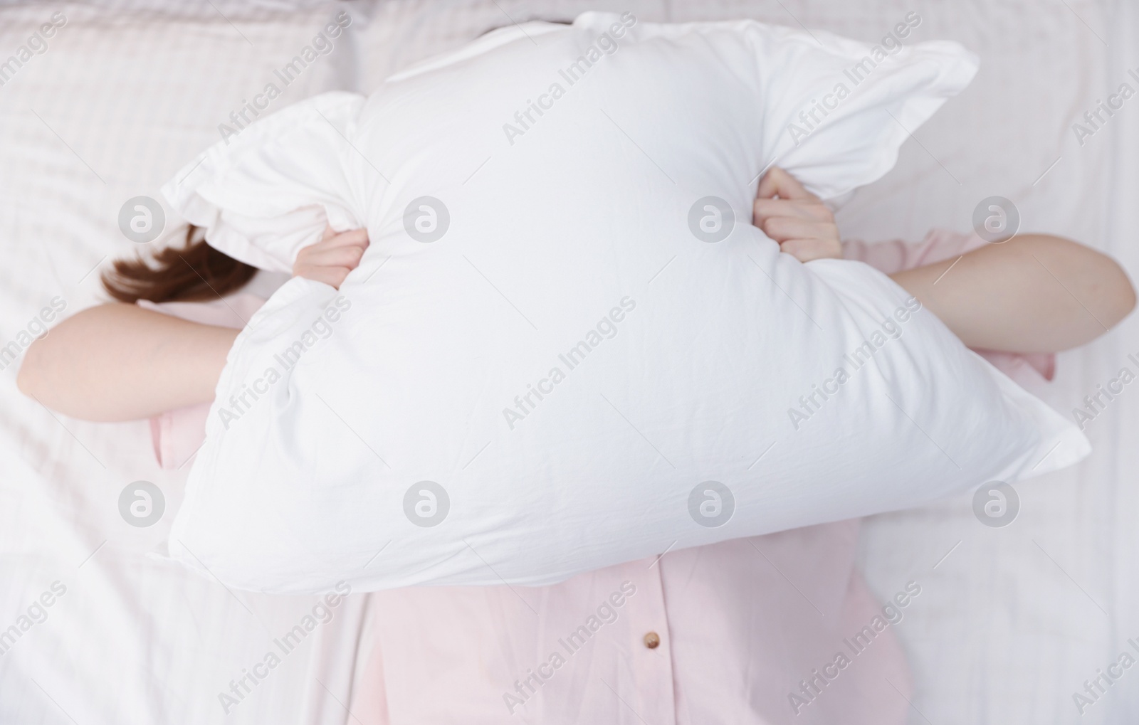 Woman covering herself with pillow on bed at home, above view. Insomnia problem Photo of Woman covering herself with pillow on bed at home, above view. Insomnia problem