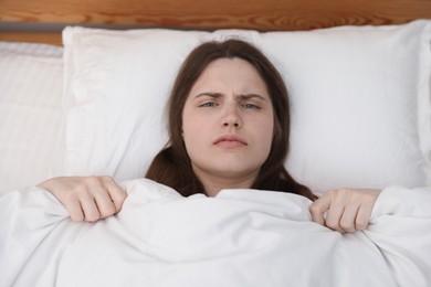 Photo of Frustrated young woman on bed at home, above view. Insomnia problem