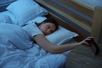 Photo of Frustrated young woman suffering from insomnia on bed indoors