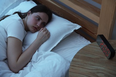 Photo of Frustrated young woman suffering from insomnia on bed indoors